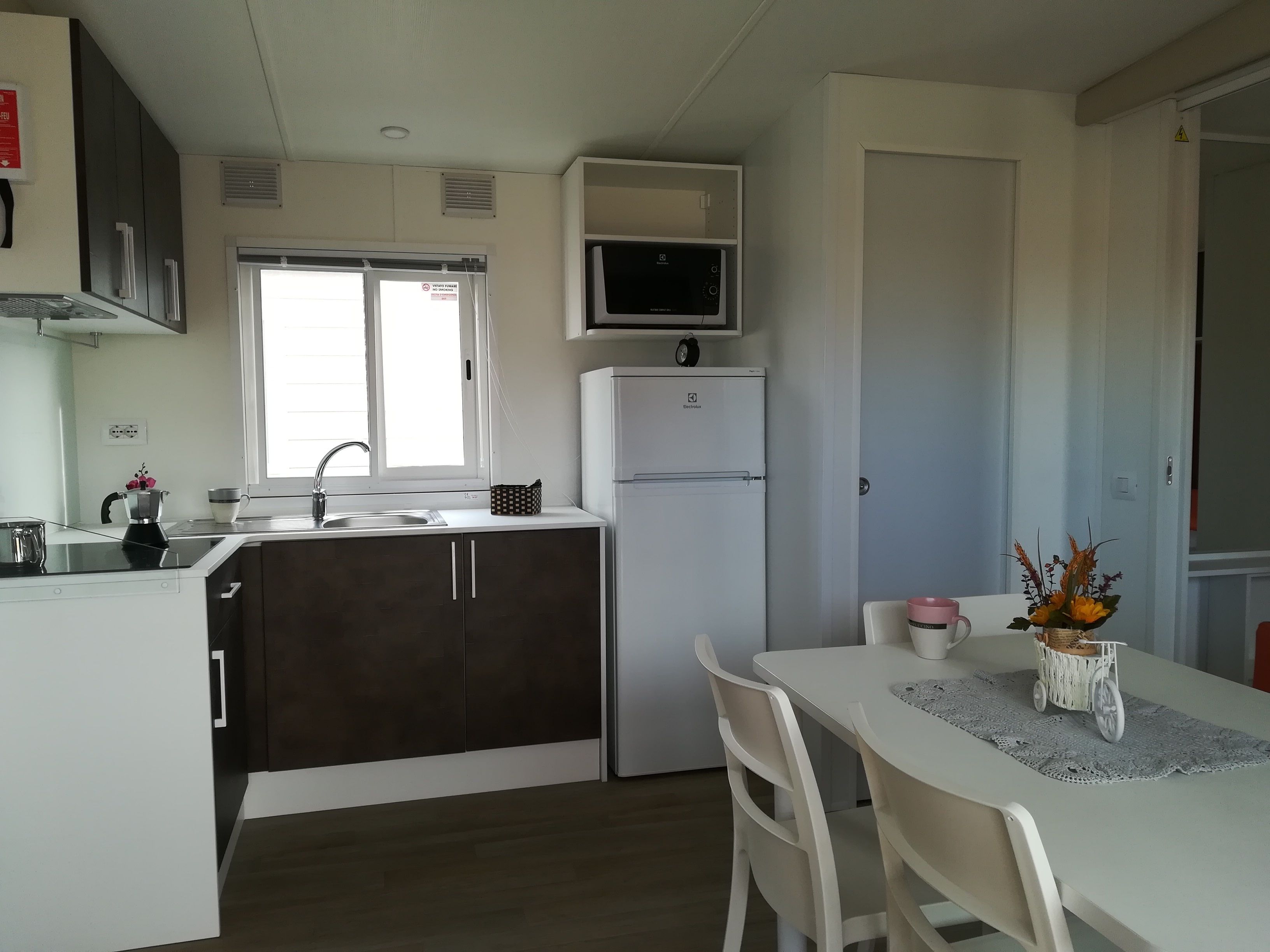 A compact kitchen with a refrigerator, microwave, and a window.