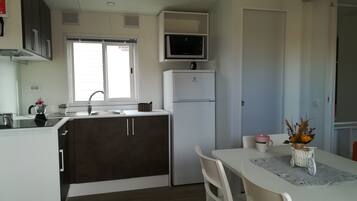 A compact kitchen with a refrigerator, microwave, and a window.