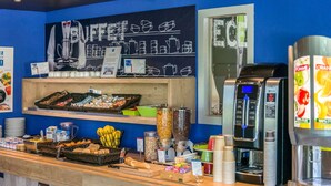 A breakfast buffet with various food items, a coffee machine, and a chalkboard menu. - ibis budget Archamps Porte de Genève (Archamps)