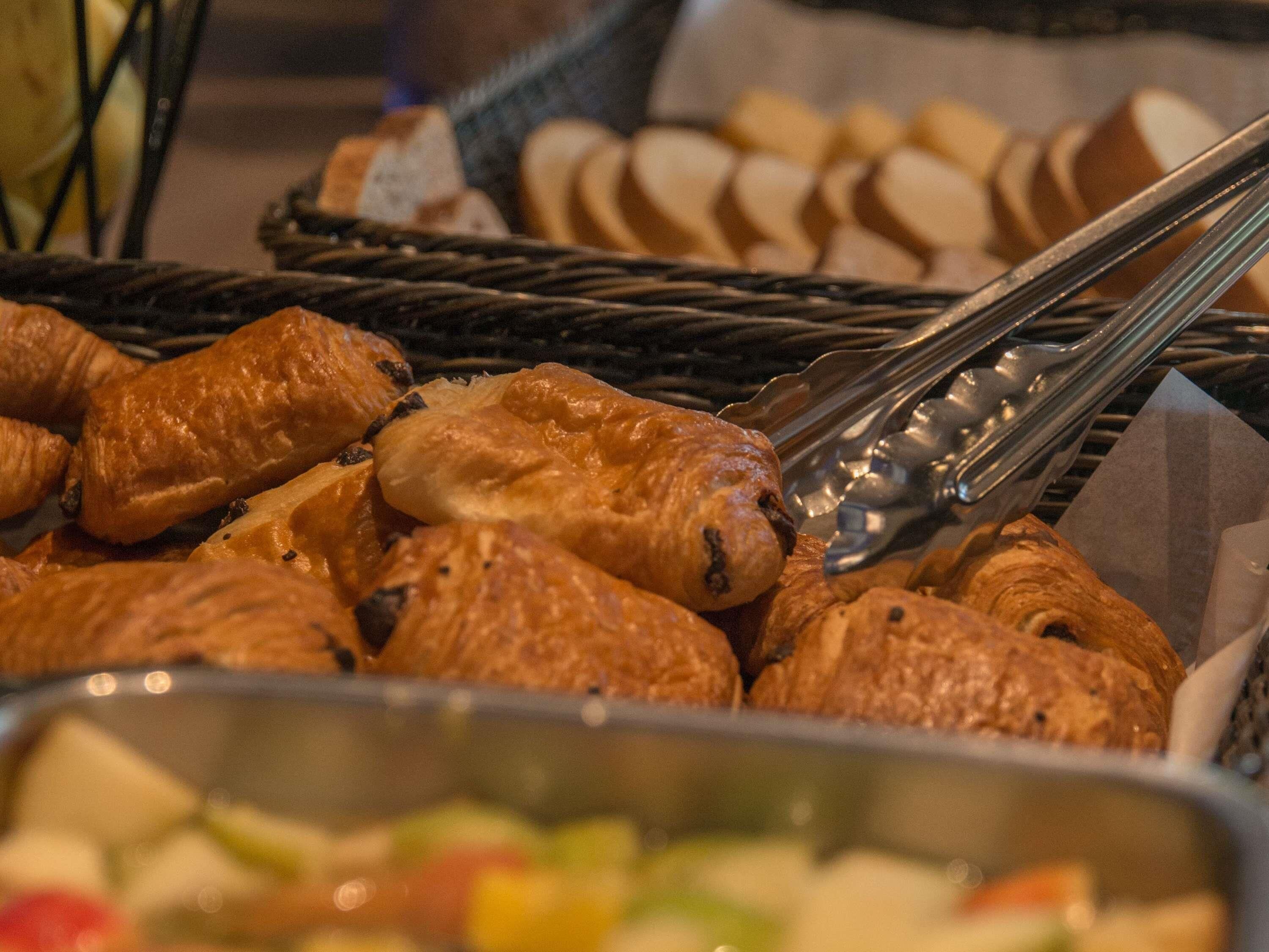 A buffet with various baked goods, including pastries and bread.