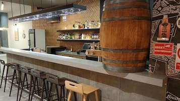 A bar area with stools, a wooden barrel, and shelves of bottles.