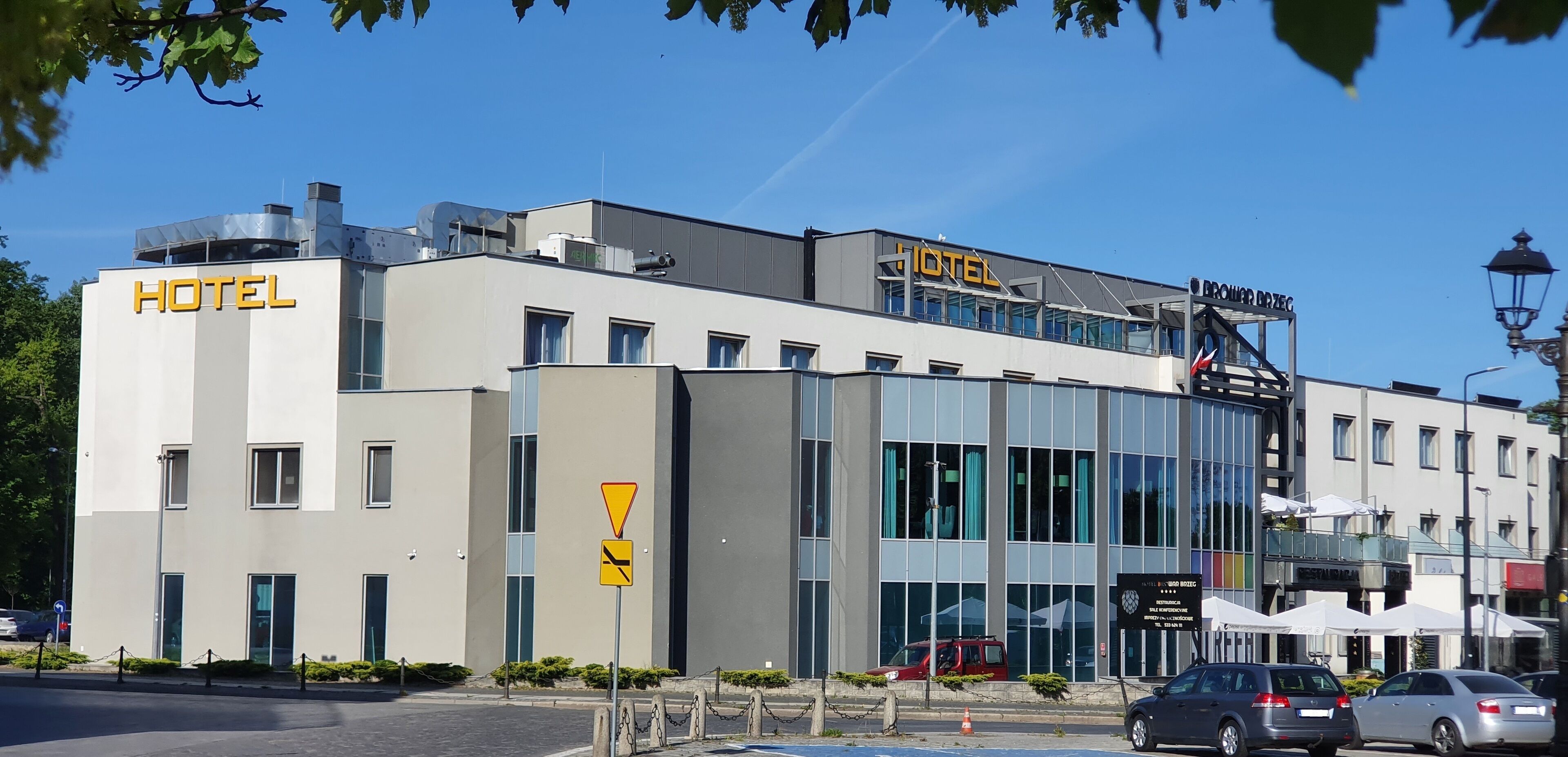 A modern hotel building with a prominent 'HOTEL' sign, large windows, and a visible entrance.
