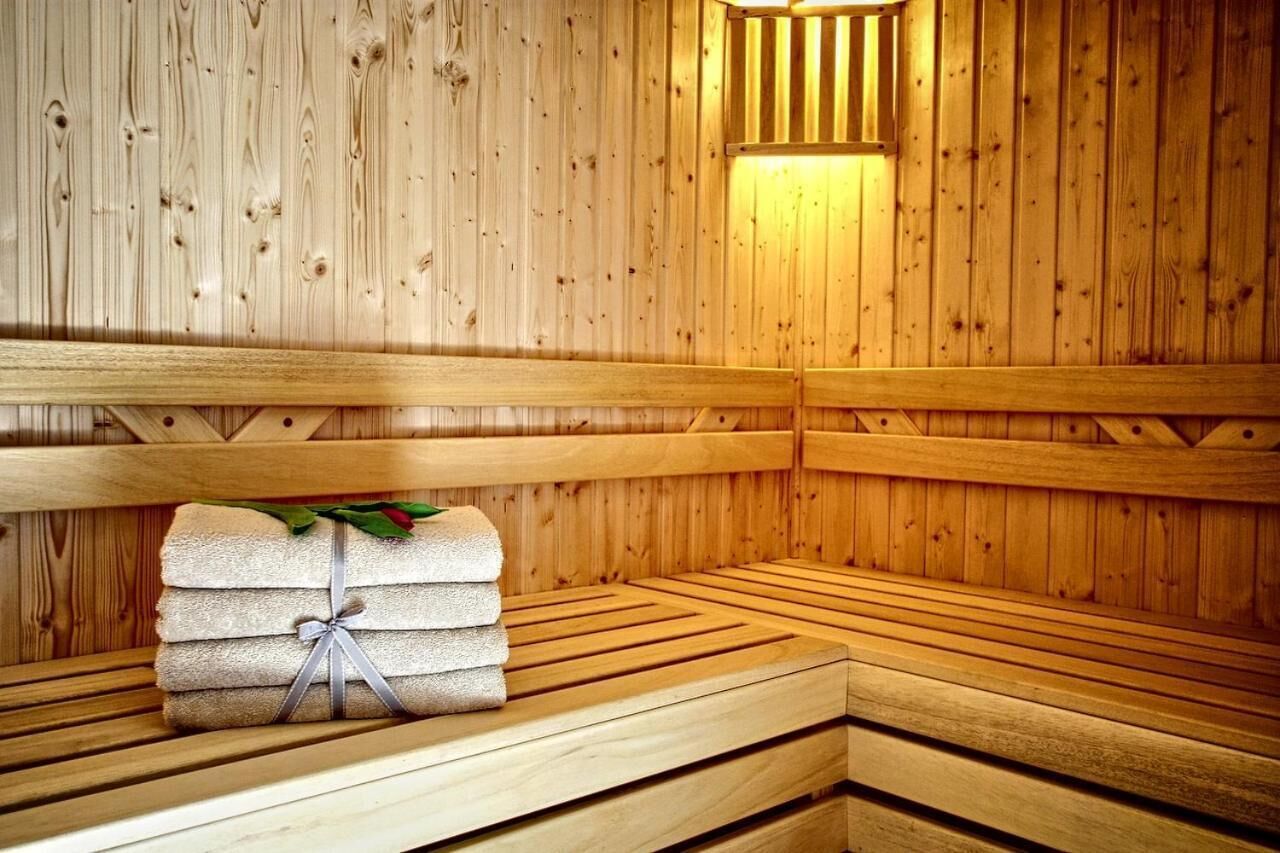 A wooden sauna with benches and a stack of towels.