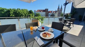 Una mesa de comedor con alimentos para el desayuno y vista a un paisaje urbano con edificios históricos.