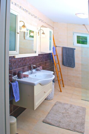 Un baño con lavamanos, espejo y toallero.
