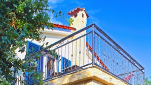 Ein Steinhaus mit Balkon, Sitzgelegenheiten im Freien und einer Treppe, die zu einer oberen Etage führt.