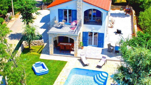 Ein zweistöckiges Haus mit Swimmingpool, Solaranlage und Balkon.