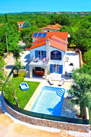 A two-story house with a swimming pool, solar panels, and a balcony.