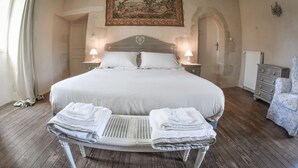 A large bed with white linens, two bedside lamps, a wooden headboard, and a painting above. - Château de la Grand'Cour (Grandchamp-des-Fontaines)