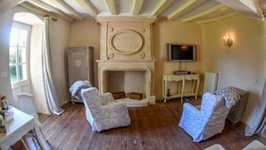 A room with a fireplace, two armchairs, a television, and a cabinet. - Château de la Grand'Cour (Grandchamp-des-Fontaines)