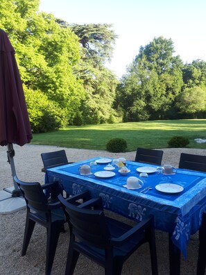 Een buiten eethoek met een tafel voor vier personen, omringd door stoelen en een tafelkleed met een blauw patroon.