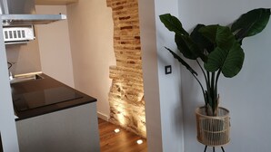 Una cocina moderna con una pared de ladrillo decorativa, una estufa empotrada y una planta en maceta.