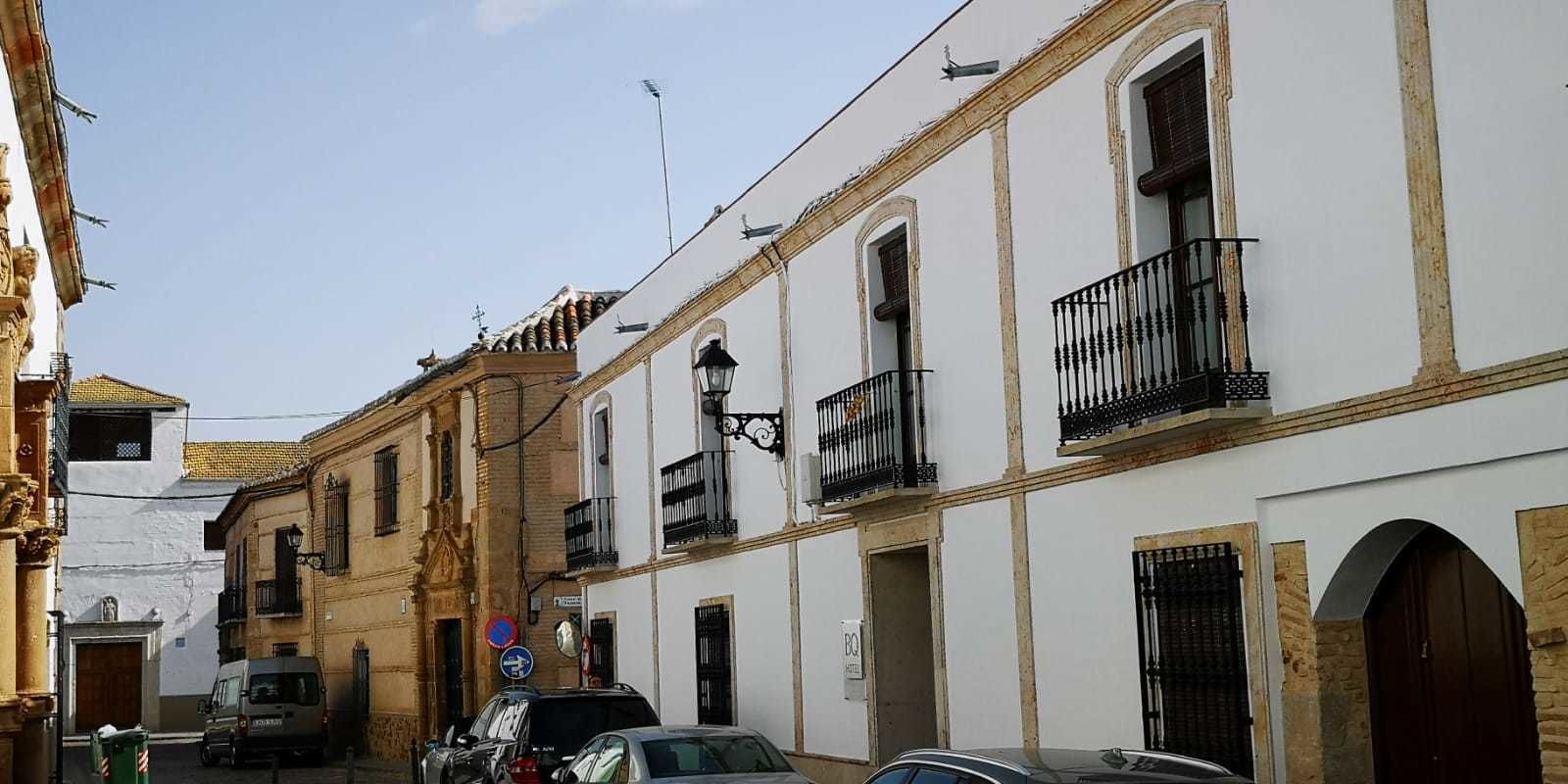 A narrow street with buildings featuring balconies and a mix of architectural styles.
