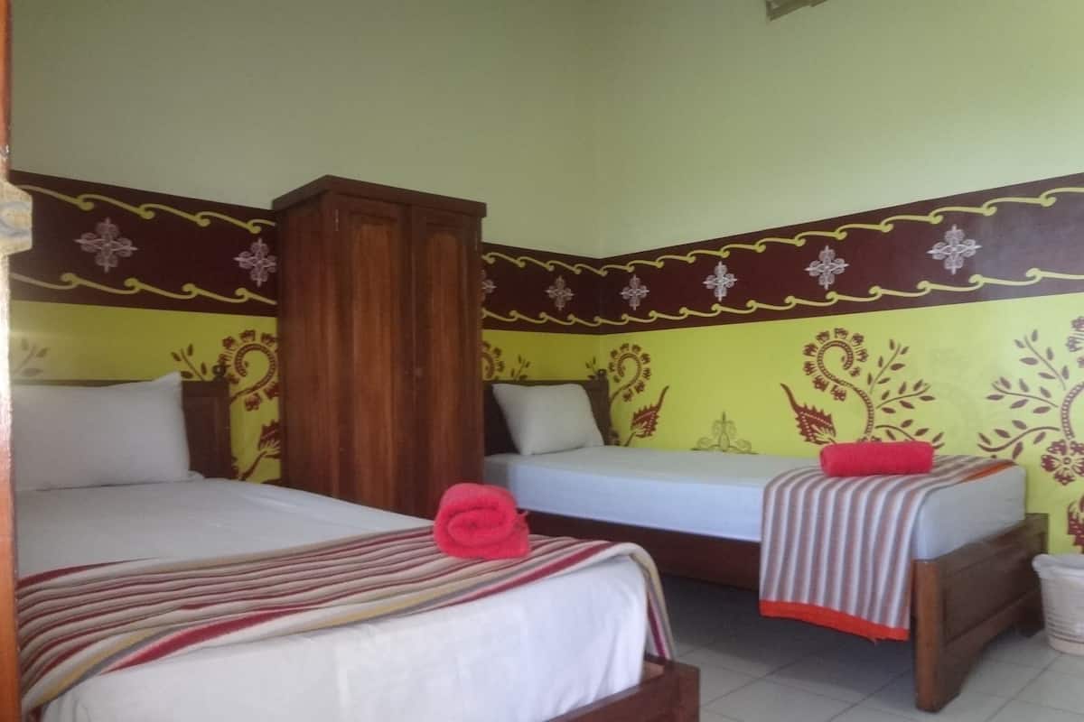 A room with two beds, a wooden wardrobe, and patterned walls.