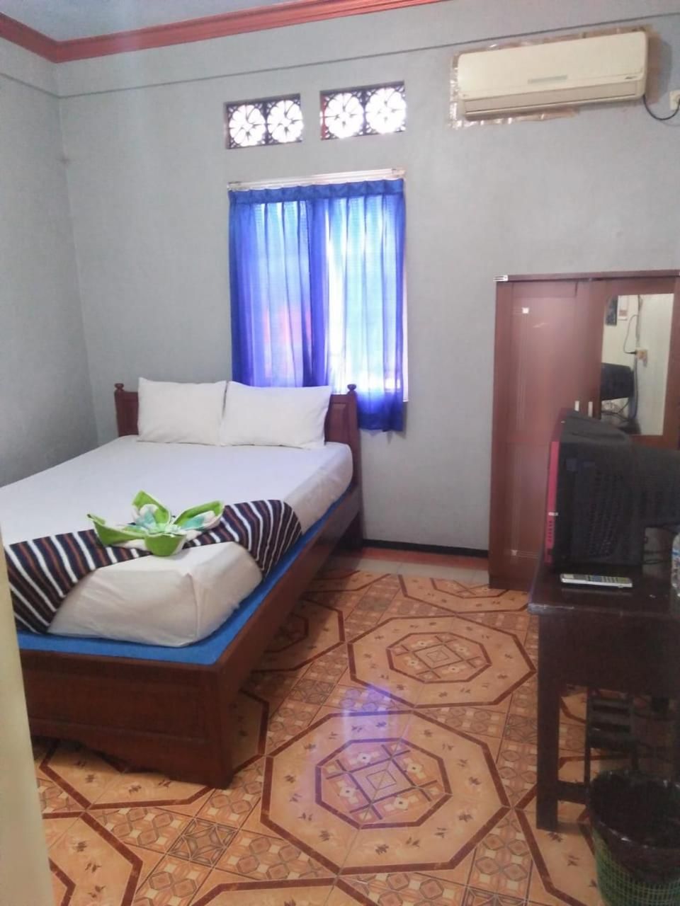 Habitación de hotel con cama, escritorio y ventana con cortinas.