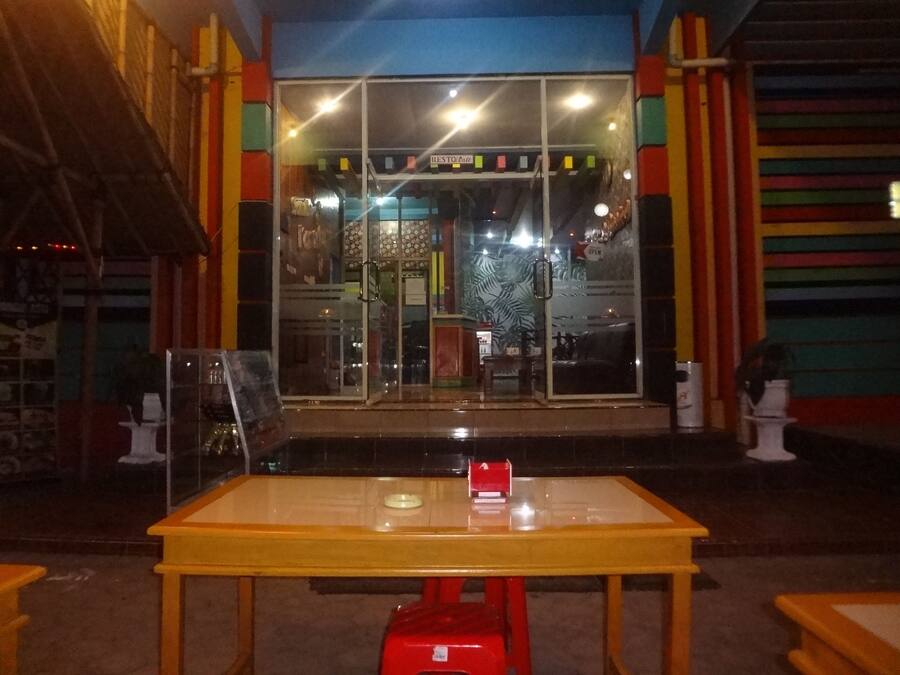 A restaurant with a glass entrance, outdoor seating, and colorful vertical stripes on the walls.