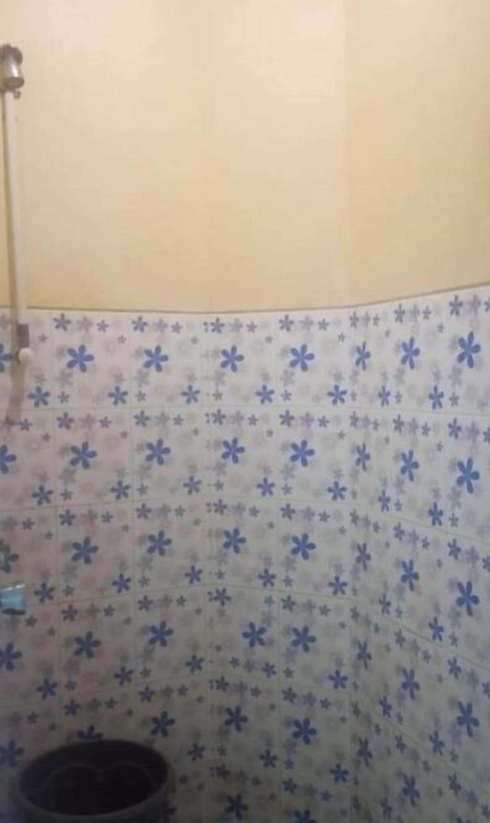 Un baño con pared de azulejos estampados y zona de ducha.