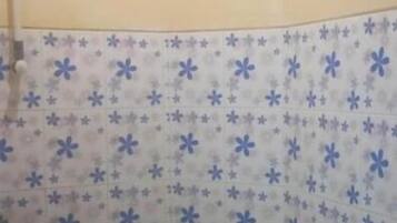 Un baño con pared de azulejos estampados y zona de ducha.