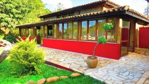 A building with a red exterior, large windows, and a stone-tiled patio. - Praia da Crioula (Vargem Bonita)