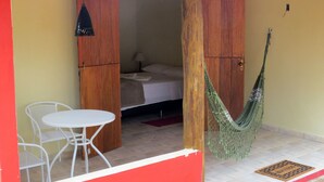 A room with a bed, a hammock, a table, and chairs. - Praia da Crioula (Vargem Bonita)