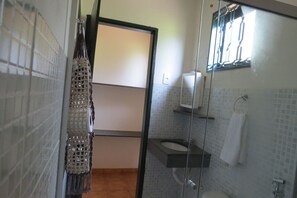 Une salle de bain avec une douche à parois de verre, des toilettes, un lavabo et un porte-serviettes.