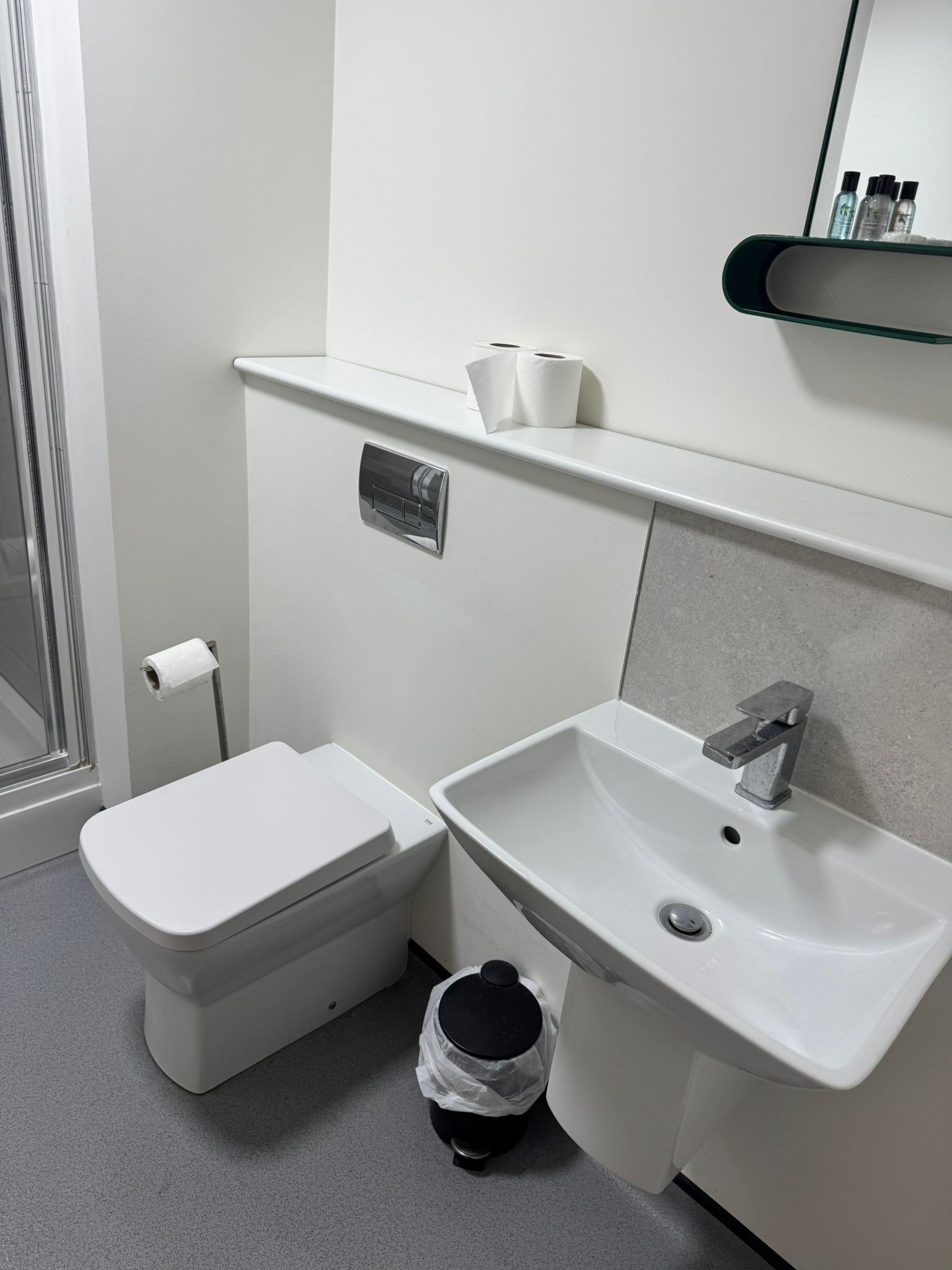 Baño con inodoro, lavamanos y un cubo de basura.