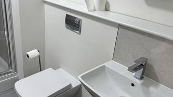 Baño con inodoro, lavamanos y un cubo de basura.
