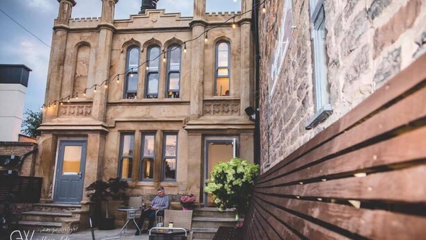 A historic building with a stone facade, large windows, and a wooden bench outside. - George Wright Boutique Hotel, Bar & Restaurant. (Rotherham)