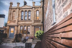 A historic building with a stone facade, large windows, and a wooden bench outside. - George Wright Boutique Hotel, Bar & Restaurant. (Rotherham)