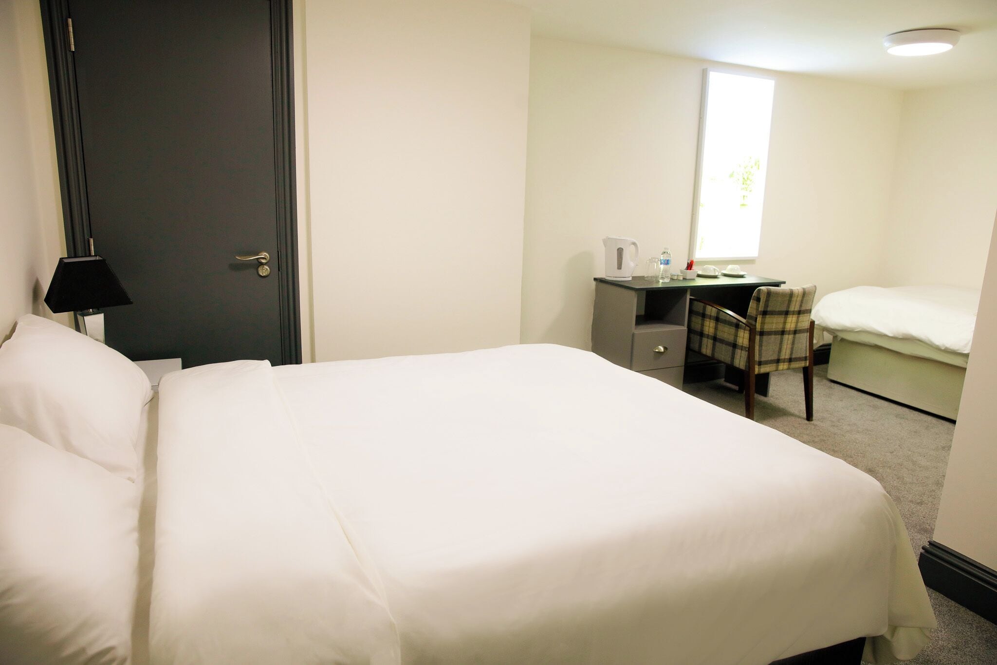 Una habitación de hotel con una cama, un escritorio, una silla y una ventana.