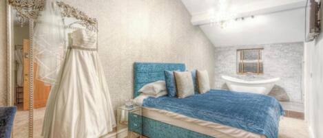 Un dormitorio con una cama grande, un tocador con espejo y un vestido en el suelo.