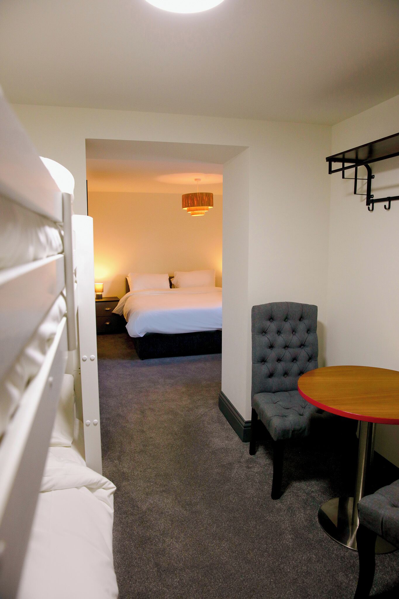 A hotel room with a bed, a chair, a table, and a nightstand.