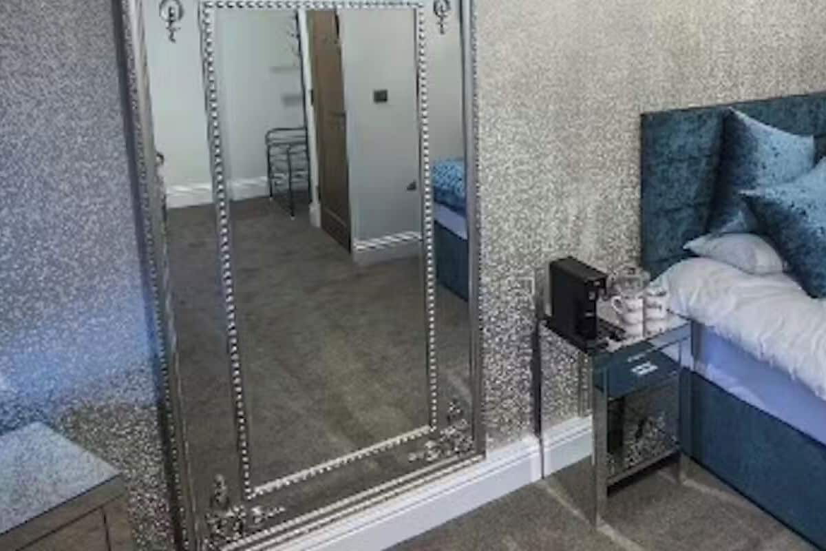 A bedroom with a large bed, a nightstand, a mirror, and a clawfoot bathtub.