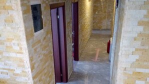 Un pasillo con paredes enlosetadas y suelo de mármol, que conduce a una puerta al final.