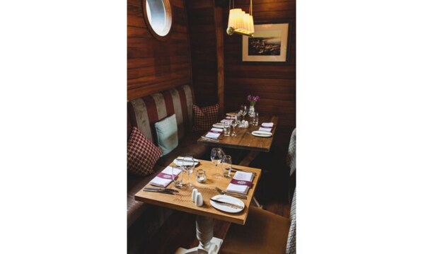 A cozy dining area with wooden tables and benches, equipped with table settings including plates, glasses, and cutlery.