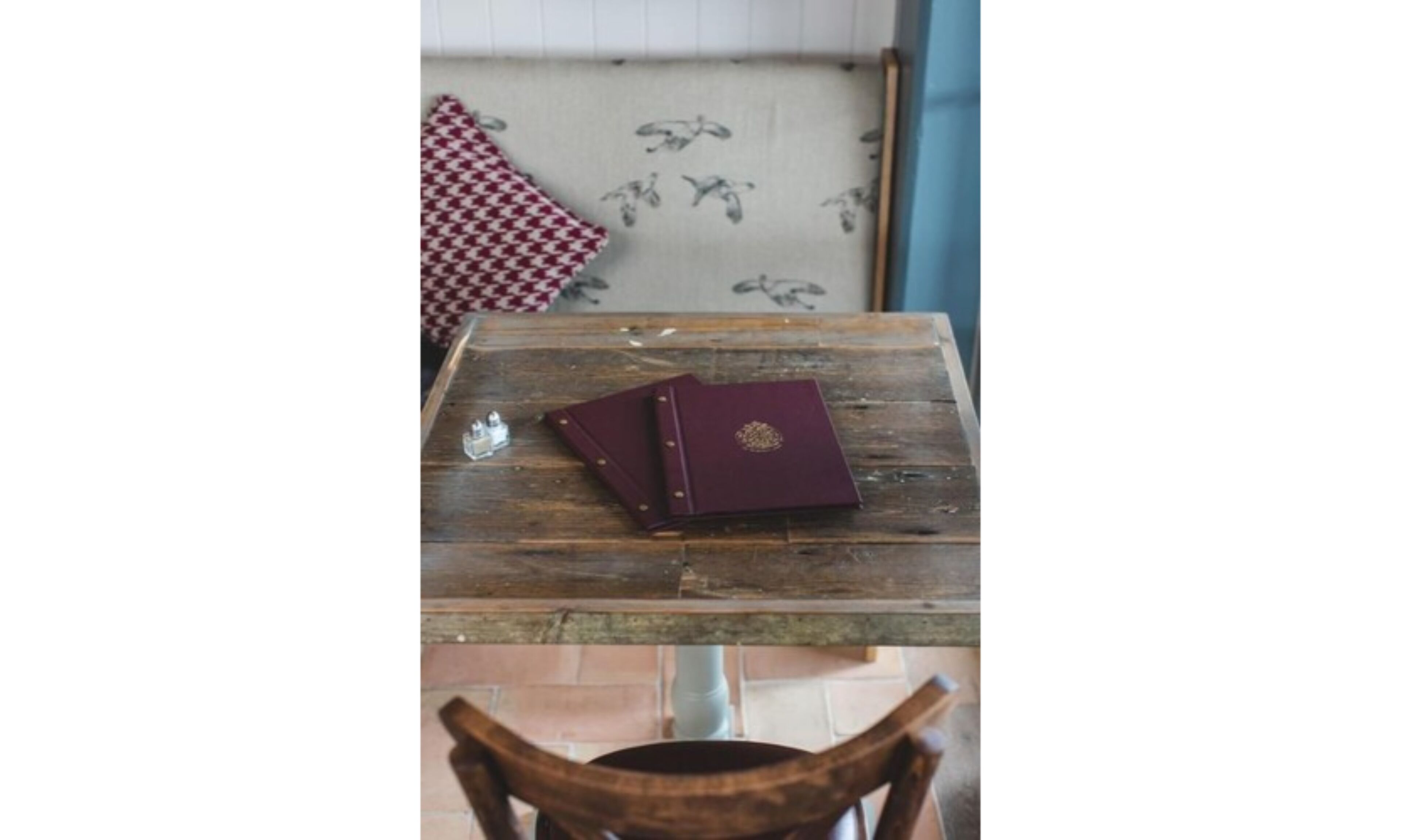 A wooden table with a closed book and a small bottle on it.