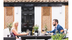 A dining area with a black door, lattice panels, and outdoor seating. - The Old Courthouse Inn (St. Brelade)