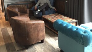 A modern living room with a staircase, leather sofas, a wooden coffee table, and a mural on the wall. - L'Attrap'Reves (Ergersheim)