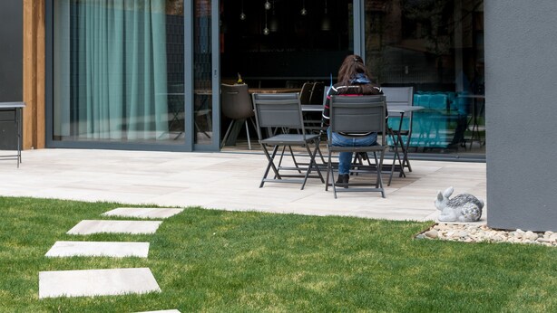 A modern outdoor patio with a dining table and chairs, a grassy area with stepping stones, and a statue of a rabbit. - L'Attrap'Reves (Ergersheim)