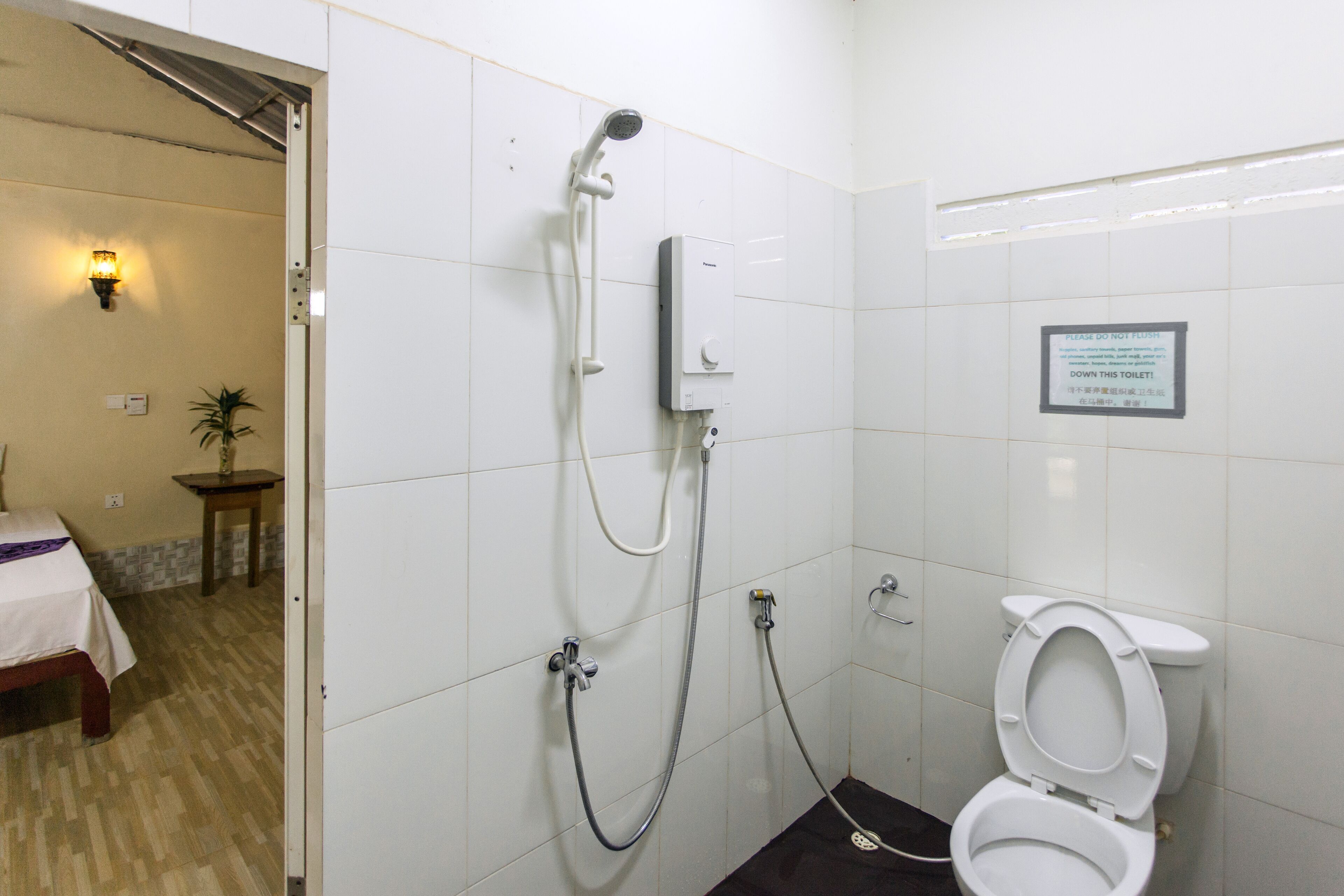 Un baño con ducha, inodoro y una cama en la habitación contigua.