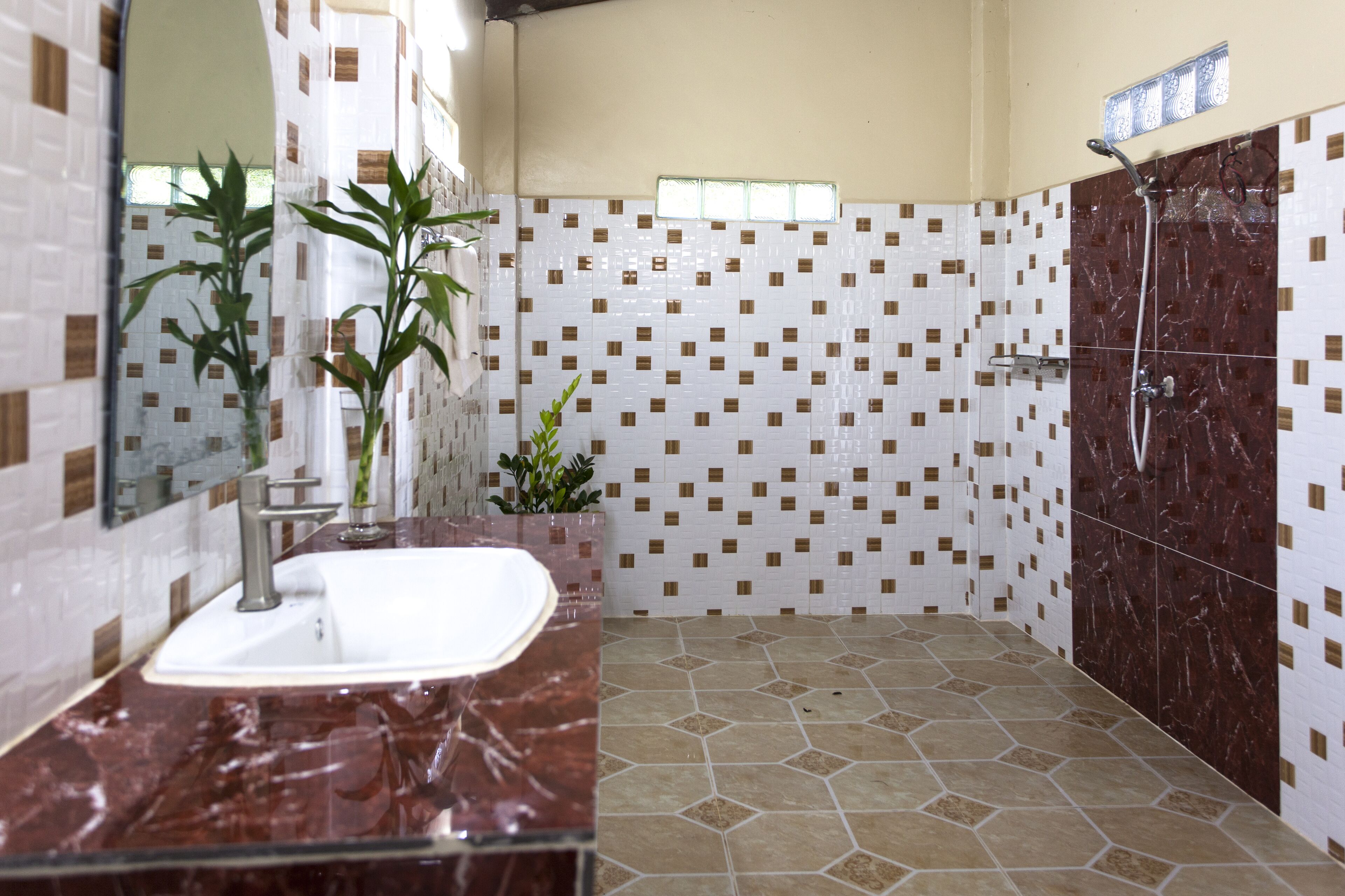 Un bagno con lavabo in marmo, doccia e pareti rivestite di piastrelle.