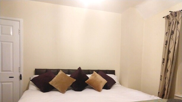Ein Schlafzimmer mit Bett, Kissen, Decke und einer Tür.