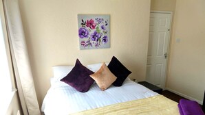 Una habitación de hotel con una cama, un cuadro de flores en la pared y una puerta.
