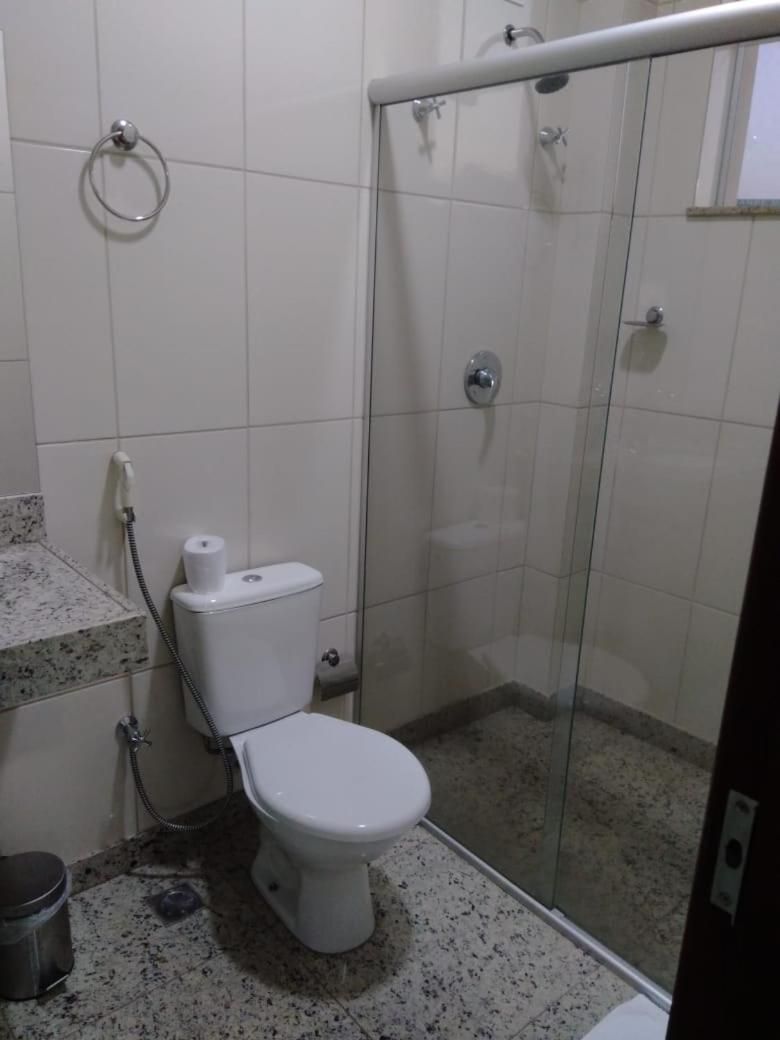 Casa de banho com sanita, chuveiro e cabine de duche com parede de vidro.