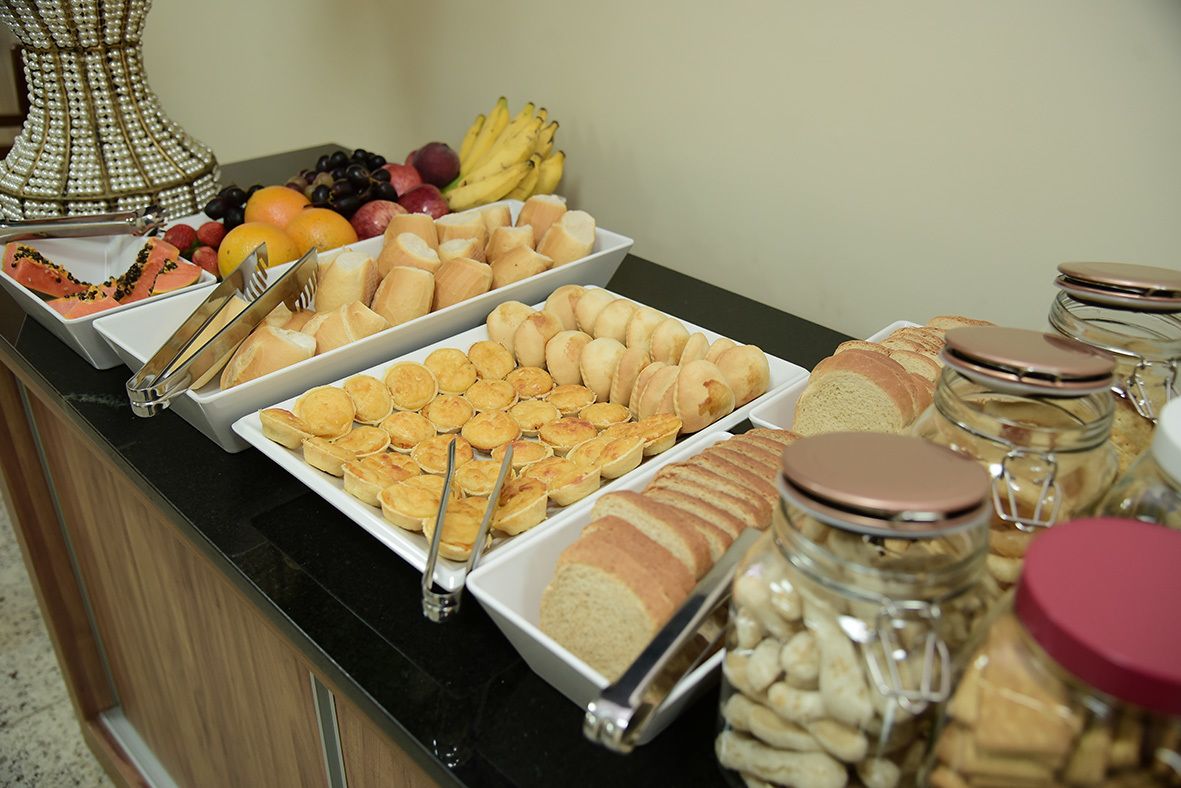 Buffet com diversas opções de comida, incluindo frutas, doces e pães.