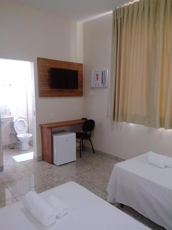 Une chambre d’hôtel comprenant un lit, un bureau, une chaise, une télévision et une salle de bain.