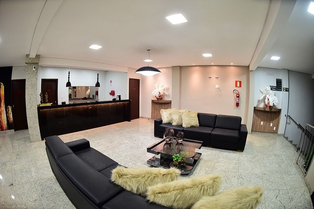 Un vestíbulo moderno con una recepción, sofás negros, una mesa de centro de vidrio y un espejo grande.