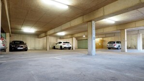 A multi-level parking garage with concrete pillars and overhead lighting. - Hotel Haus am Berg (Trier)