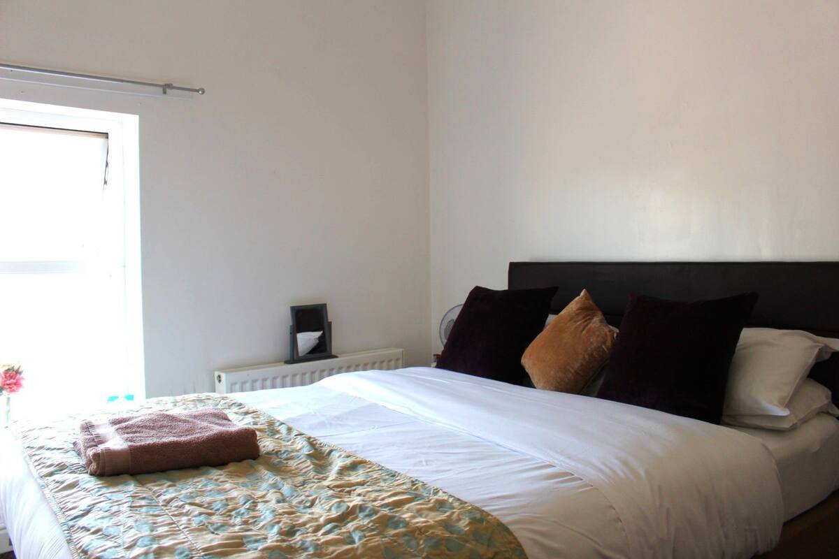 A neatly made bed with a brown towel, a white comforter, and multiple pillows.