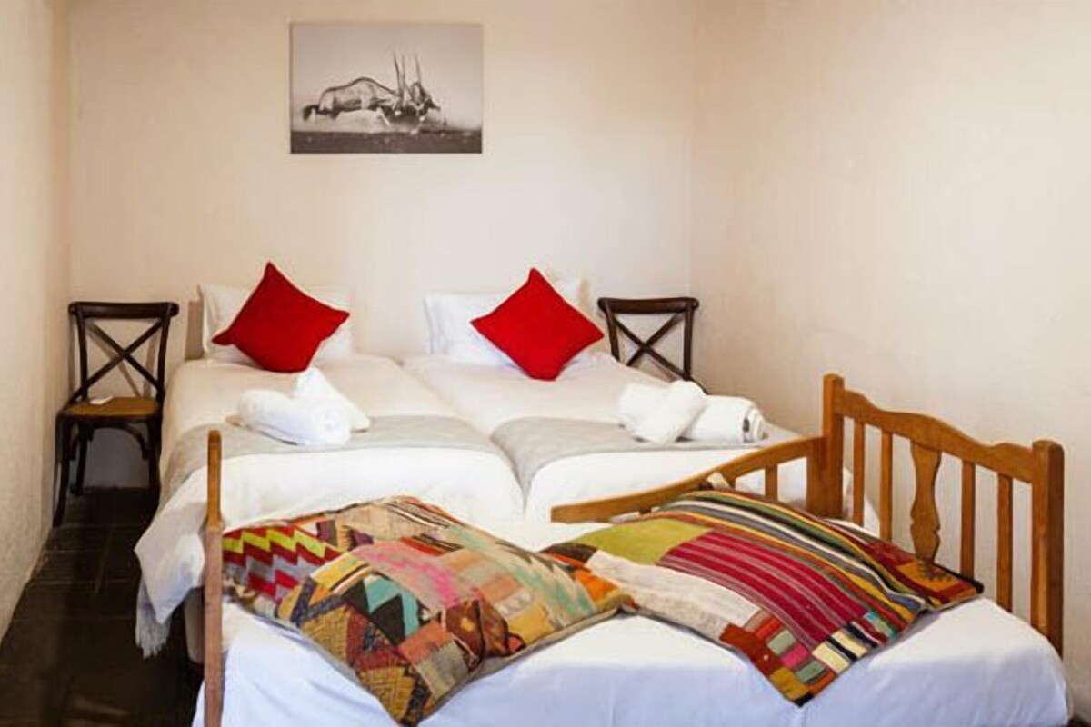 A double bed with two pillows, a wooden headboard, and a colorful quilt.